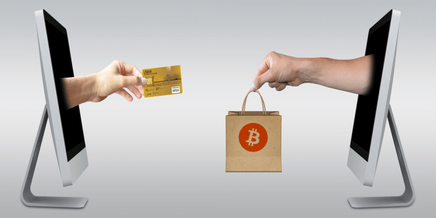 Two hands coming out of computer screens. One holds a credit card and the other holds a bag with a bitcoin logo on it. They're about to exchange it. Showing how Lolli works