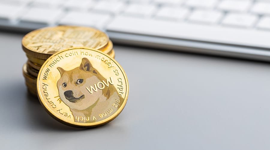 Picture of a stack of dogecoin crypto coins next to a computer keyboard. As Dogecoin gets left out of S&P Index