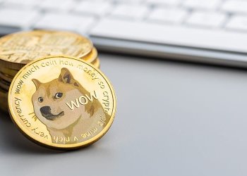 Picture of a stack of dogecoin crypto coins next to a computer keyboard. As Dogecoin gets left out of S&P Index