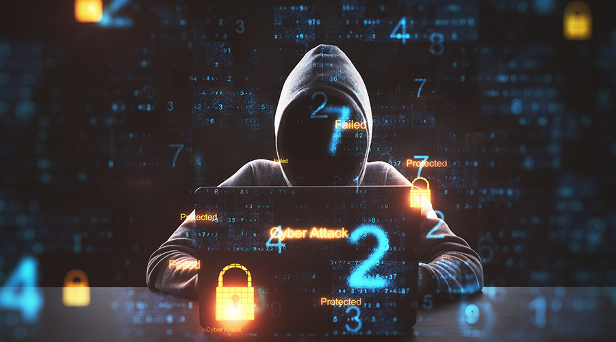 Picture of an anonymous hacker in front of a computer with computer code around them
