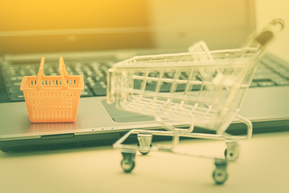 Picture of a shopping cart and basket next to a computer
