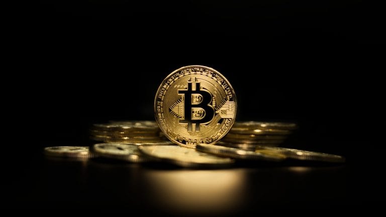 Picture of a standing Bitcoin surrounded by other bitcoins laying flat in a circle