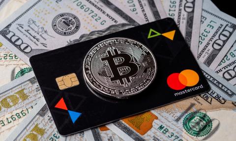 Picture of a bitcoin on top of a Mastercard, with dollar bills underneath them, as Australian exchange CoinJar release debit card