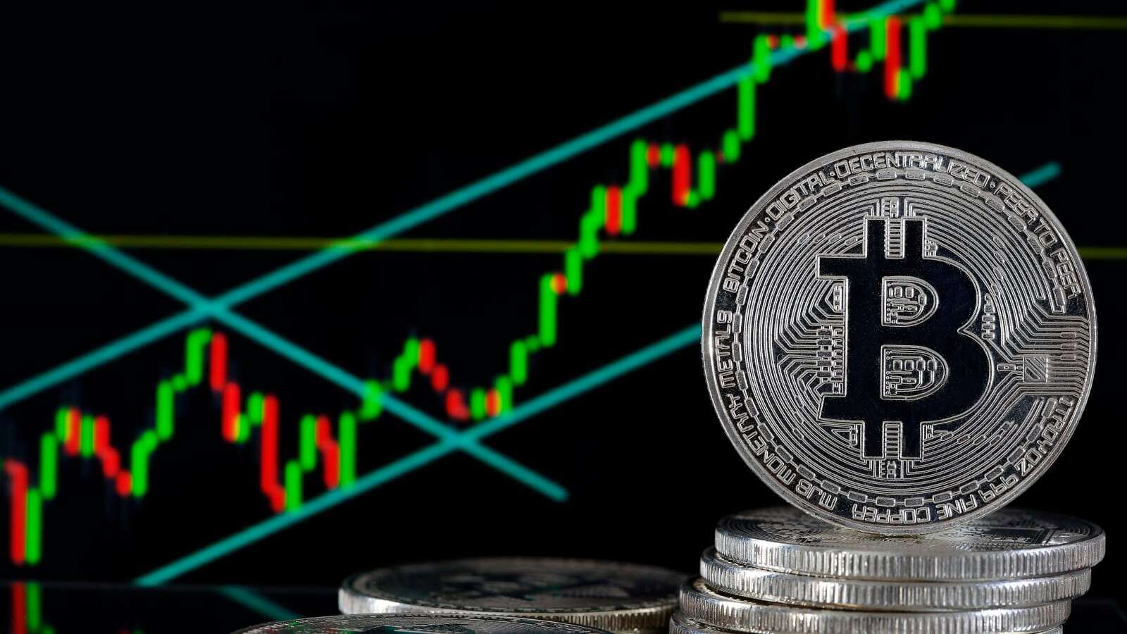 Picture of a bitcoin in front of a red and green candlestick chart