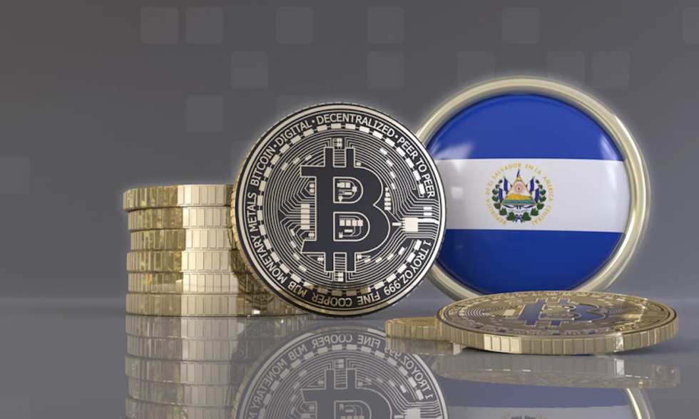 Picture of a round El Salvador flap with a silver bitcoin next to it, and a stack of coins behind the bitcoin