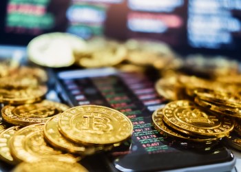 Picture of crypto coins laying on top of a cell phone with market orders displayed on it