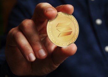 Picture of a hand holding a Solana coin