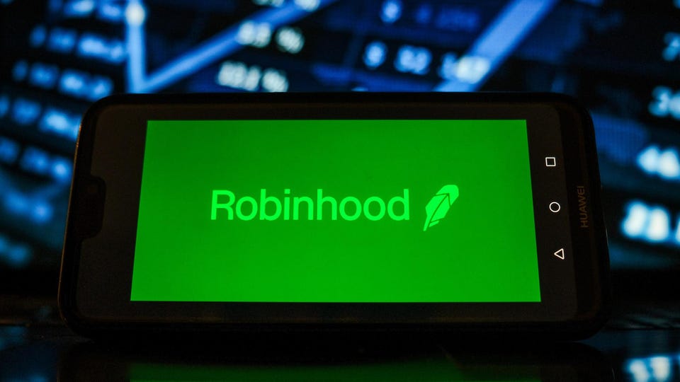 Picture of Robinhood logo on a mobile phone in front of a market chart