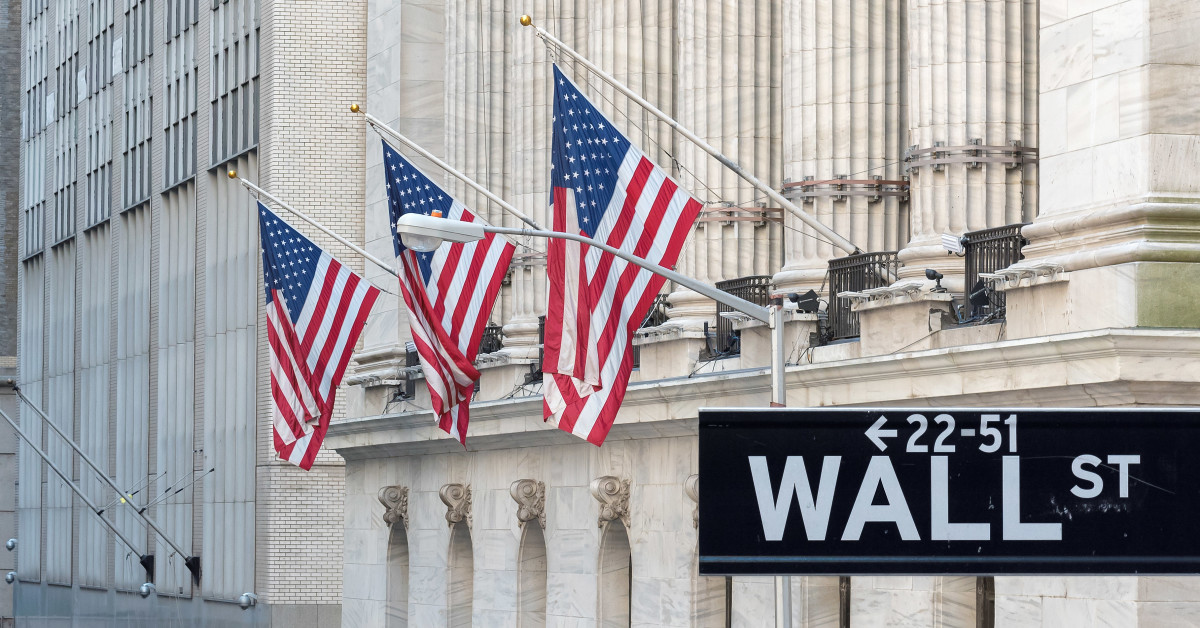 Picture of a Wall Street street sign with three American flags behind it