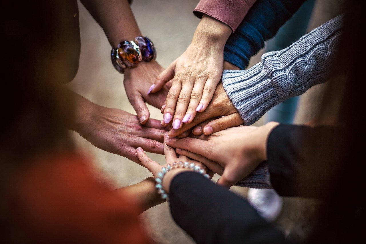 Bitcoin for Communities, hands doing the "all for one "