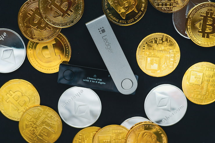 An image showing various cryptocurrency coins and the Ledger wallet in the center.